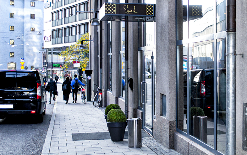 Svart skåpbil står framför restaurangentré på gatan.